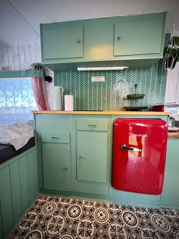 Grüne Küchenzeile mit rotem Kühlschrank im StrandCamper am Stover Strand bei Hamburg