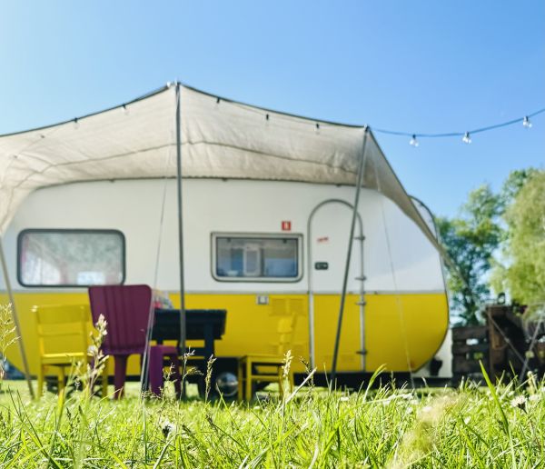 Yellow and white retro camper with sitting area at Stover Strand campsite