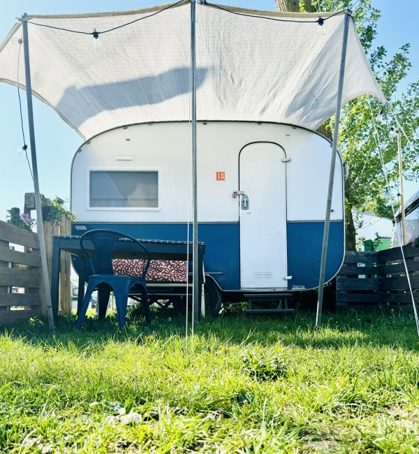 Dark blue retro camper with awning at the Stover Strand campsite near Hamburg