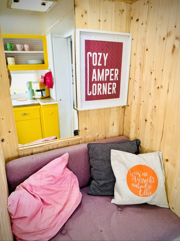 Retro camper Petronella Citronella furnished with a pink indoor sitting area at the Stover Strand campsite near Hamburg