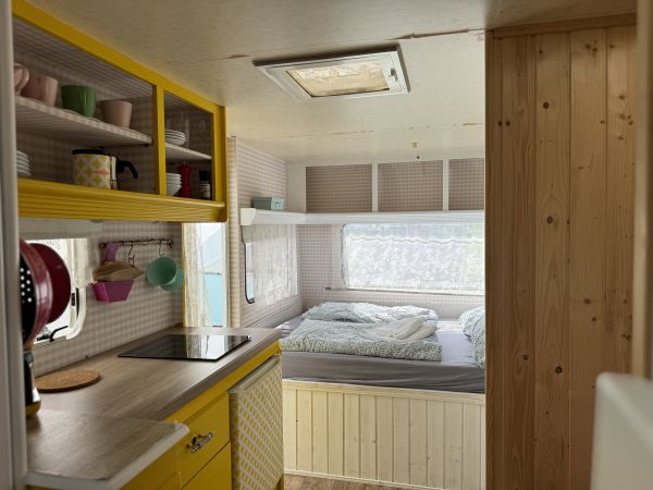 Retro camper Petronella Citronella furnished with a sitting area and double bed at Stover Strand Camping