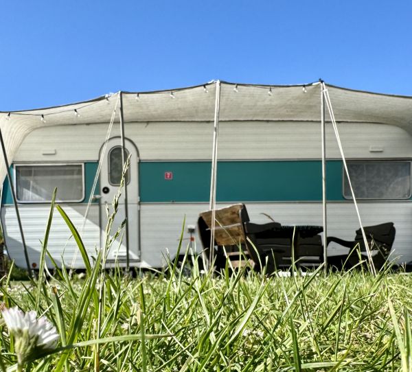 White turquoise retro camper with awning right on Stover Strand Camping