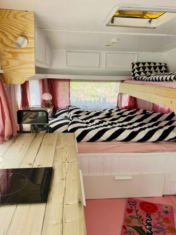 Bezogene Betten mit Küchenzeile im rosa StrandCamper am Stover Strand
